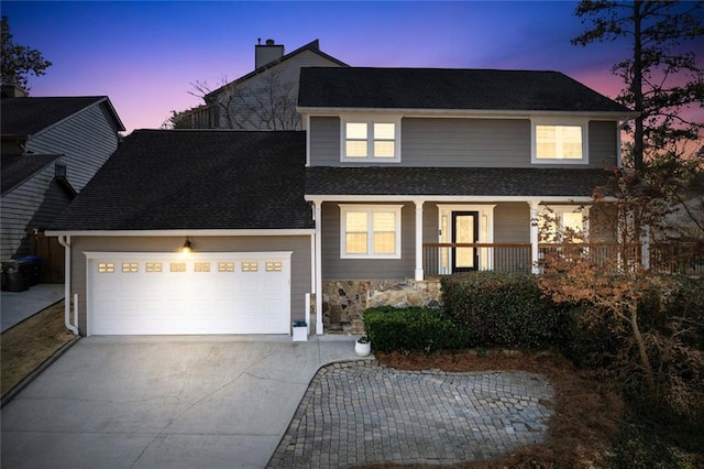 traditional-style home featuring an attached garage, covered porch, a shingled roof, driveway, and a chimney