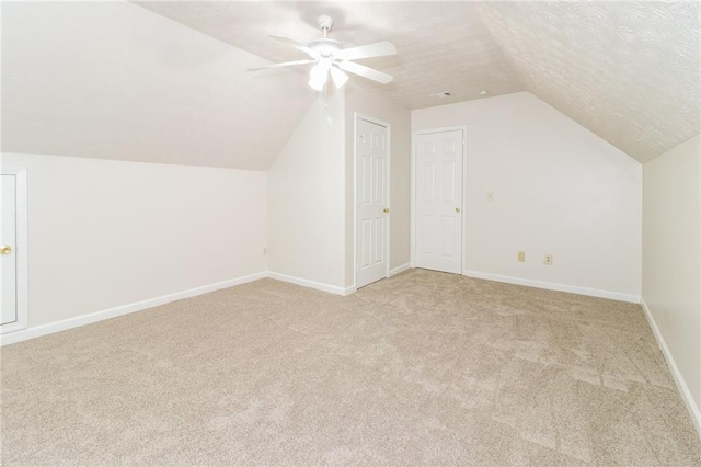 bonus room featuring lofted ceiling, a textured ceiling, light colored carpet, and ceiling fan