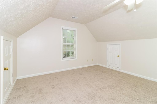 bonus room featuring a textured ceiling, light colored carpet, and vaulted ceiling