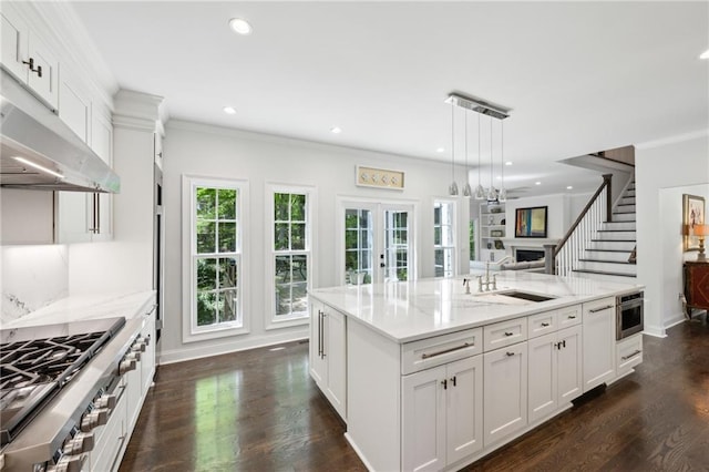 4152 Club Dr NE, Atlanta, GA 30319 - kitchen with light stone counters, a sink, stainless steel gas cooktop, a center island with sink, and white cabinetry