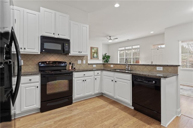 kitchen with white cabinets, kitchen peninsula, dark stone counters, and black appliances