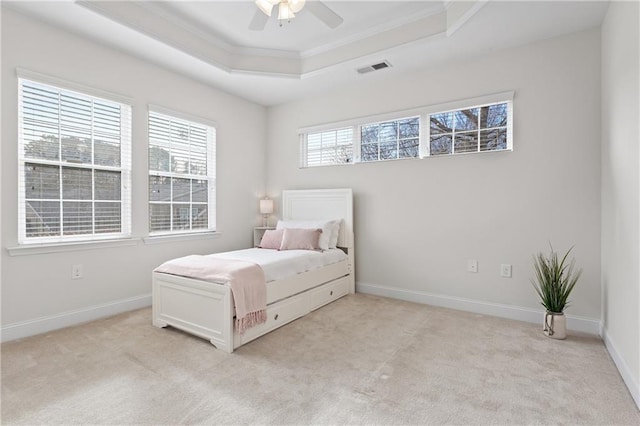 carpeted bedroom featuring ceiling fan, crown molding, and a tray ceiling