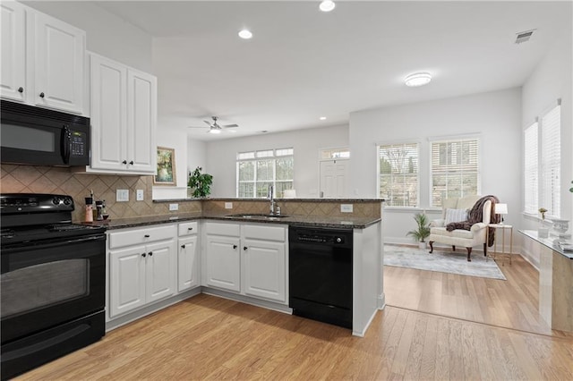 kitchen featuring black appliances, white cabinets, dark stone counters, and sink