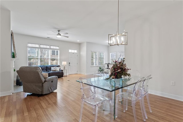 dining space featuring ceiling fan with notable chandelier and wood-type flooring