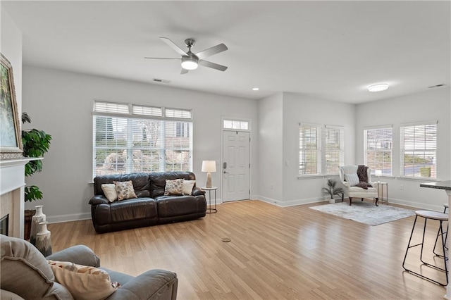 living room featuring ceiling fan, a healthy amount of sunlight, and light wood-type flooring