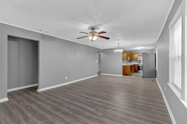 unfurnished living room featuring crown molding, ceiling fan with notable chandelier, dark wood-type flooring, and a textured ceiling