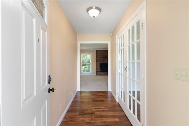 hallway featuring dark wood-style flooring, baseboards, and visible vents