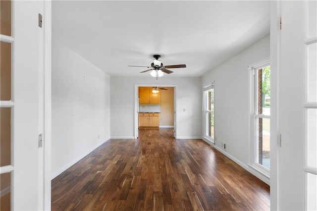 empty room featuring dark wood-style flooring, a ceiling fan, and baseboards