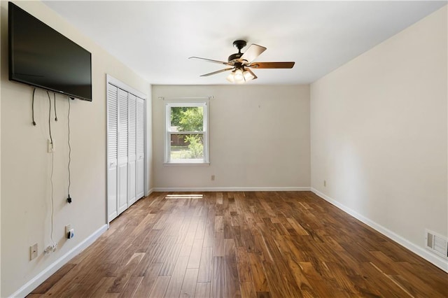 unfurnished bedroom featuring visible vents, baseboards, wood finished floors, and a closet
