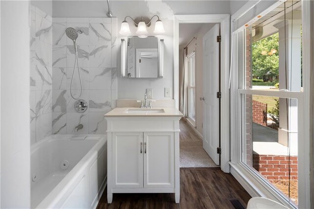 bathroom featuring vanity, a combined bath / shower with jetted tub, visible vents, and wood finished floors