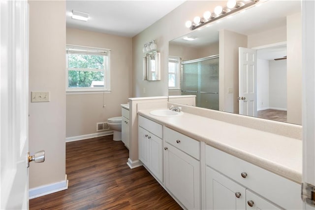 bathroom featuring vanity, toilet, baseboards, visible vents, and a stall shower