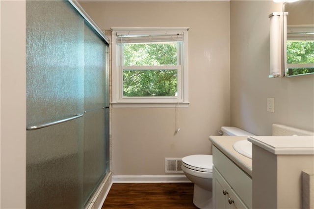 full bathroom with vanity, wood finished floors, toilet, baseboards, and a shower with shower door