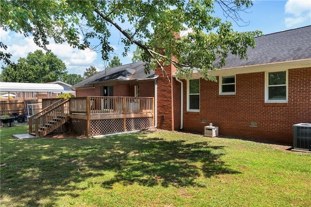 rear view of property featuring brick siding, central AC unit, and a lawn