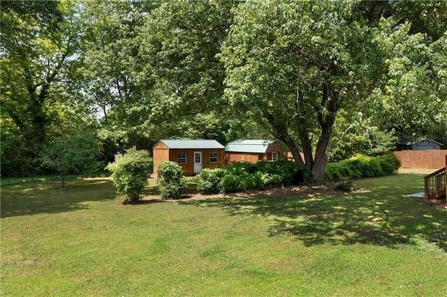 view of yard with fence, an outdoor structure, and a shed