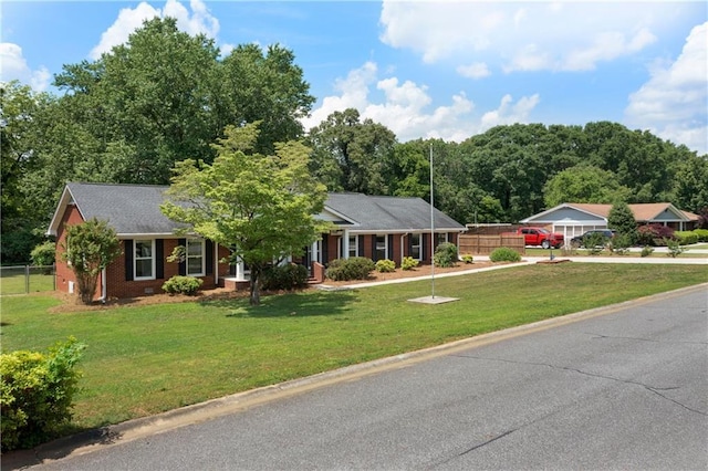 ranch-style home featuring brick siding, fence, driveway, and a front yard