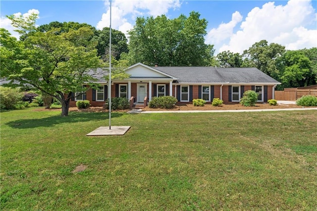 view of front facade featuring brick siding, fence, a front yard, and a porch