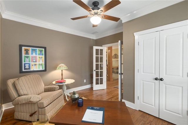 sitting room featuring french doors, ornamental molding, a ceiling fan, wood finished floors, and baseboards