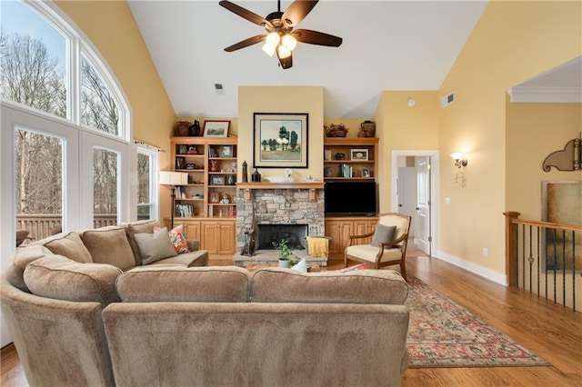 living room with high vaulted ceiling, light wood-style flooring, visible vents, and a stone fireplace