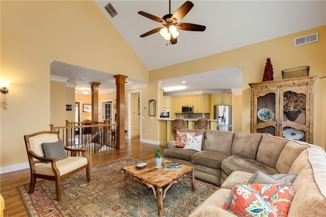 living area with wood finished floors, visible vents, baseboards, ornamental molding, and decorative columns