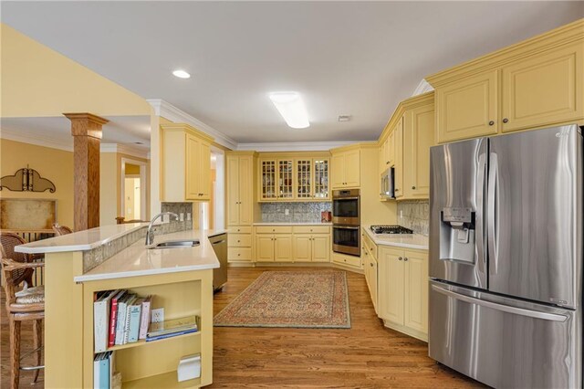 kitchen featuring a breakfast bar area, a peninsula, stainless steel appliances, light countertops, and a sink