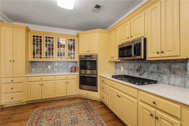 kitchen featuring dark wood-type flooring, visible vents, light countertops, appliances with stainless steel finishes, and glass insert cabinets