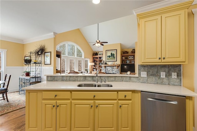 kitchen with a sink, a peninsula, light countertops, and stainless steel dishwasher