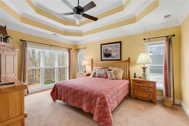 bedroom featuring light carpet, visible vents, baseboards, a tray ceiling, and crown molding