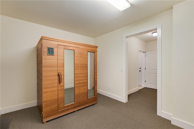 unfurnished bedroom featuring baseboards and dark colored carpet