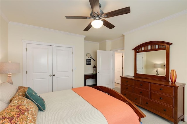 carpeted bedroom with ceiling fan, ornamental molding, and a closet