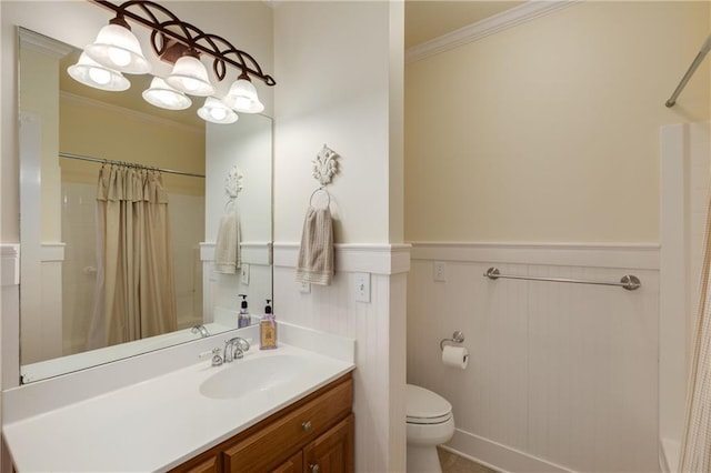 bathroom with toilet, vanity, ornamental molding, and wainscoting