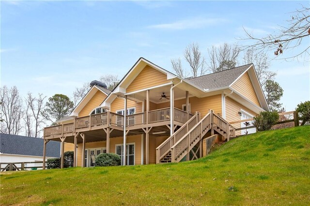 rear view of house featuring a deck, a garage, a ceiling fan, stairs, and a lawn