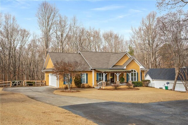 view of front of home featuring driveway, a garage, fence, and a porch