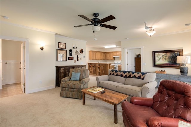 living area with baseboards, ornamental molding, a ceiling fan, and light colored carpet