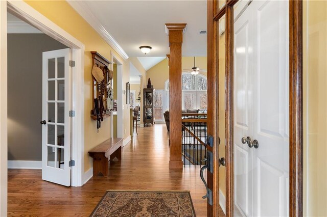 hallway with crown molding, visible vents, an upstairs landing, wood finished floors, and baseboards