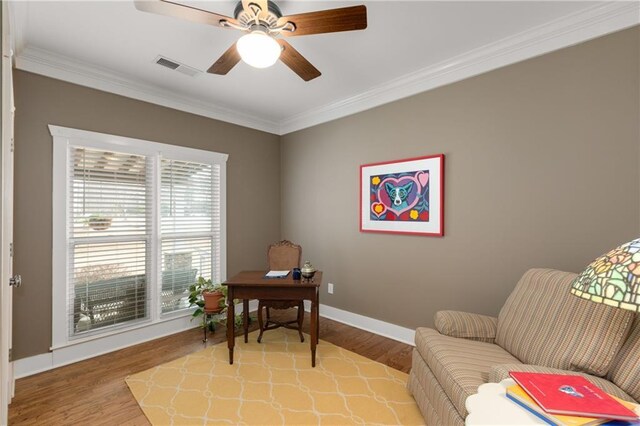 office featuring baseboards, visible vents, a ceiling fan, ornamental molding, and light wood-style floors