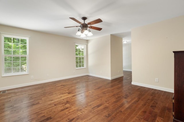 empty room featuring ceiling fan, plenty of natural light, and dark wood-type flooring