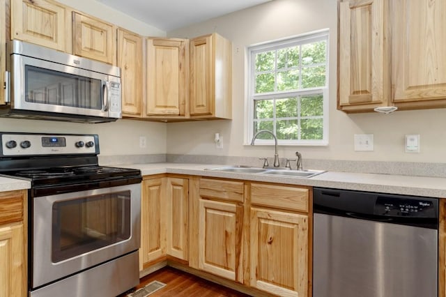 kitchen featuring appliances with stainless steel finishes, light brown cabinets, dark hardwood / wood-style flooring, and sink