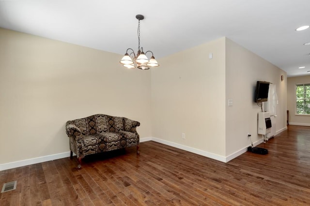 sitting room featuring heating unit, dark hardwood / wood-style floors, and a notable chandelier