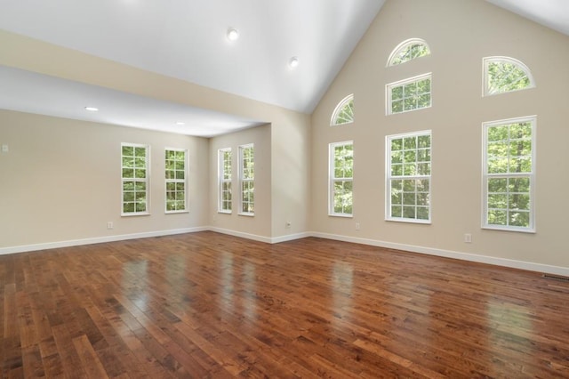 unfurnished room featuring a towering ceiling and dark wood-type flooring