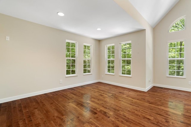 unfurnished room featuring dark hardwood / wood-style floors and vaulted ceiling