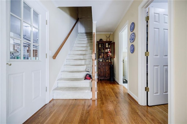 foyer entrance with wood-type flooring and ornamental molding