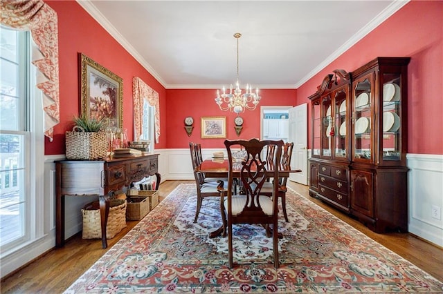 dining room with hardwood / wood-style flooring, a notable chandelier, crown molding, and a wealth of natural light