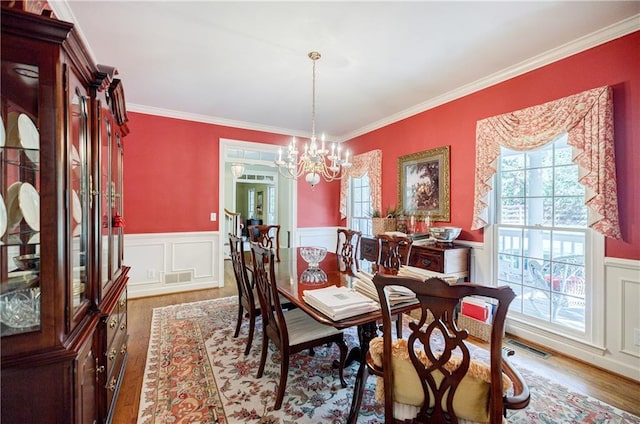 dining space with dark hardwood / wood-style floors, crown molding, and an inviting chandelier