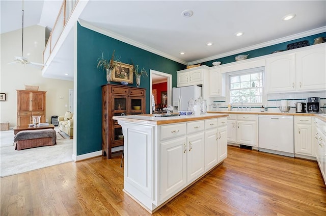 kitchen with tasteful backsplash, white appliances, a center island, light hardwood / wood-style floors, and white cabinetry