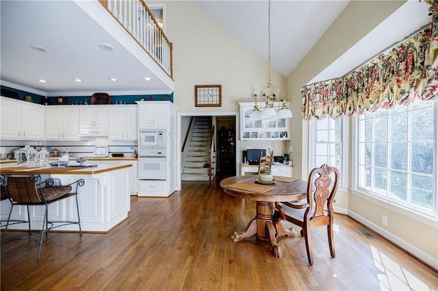 dining space featuring wood-type flooring, an inviting chandelier, and vaulted ceiling