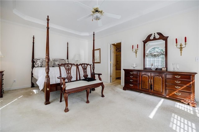 bedroom with ensuite bathroom, ceiling fan, light colored carpet, and a tray ceiling