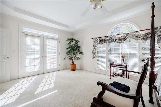 sitting room with french doors, light colored carpet, a raised ceiling, ceiling fan, and crown molding