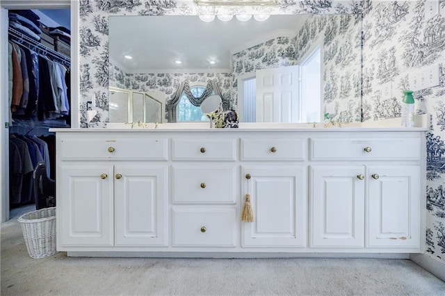 bathroom with vanity, a shower with shower door, and ornamental molding