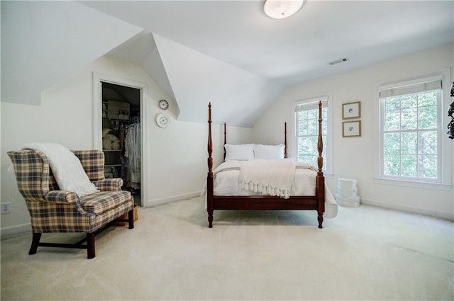 carpeted bedroom with a walk in closet, a closet, and lofted ceiling