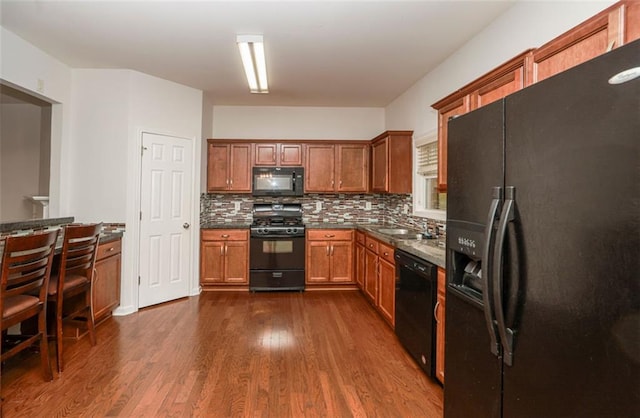5260 Sherwood Way, Cumming, GA 30040 - kitchen with black appliances, dark countertops, decorative backsplash, dark wood finished floors, and brown cabinetry